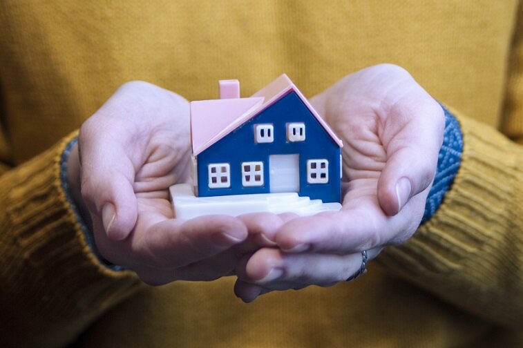 A person holding a miniature home in her hands