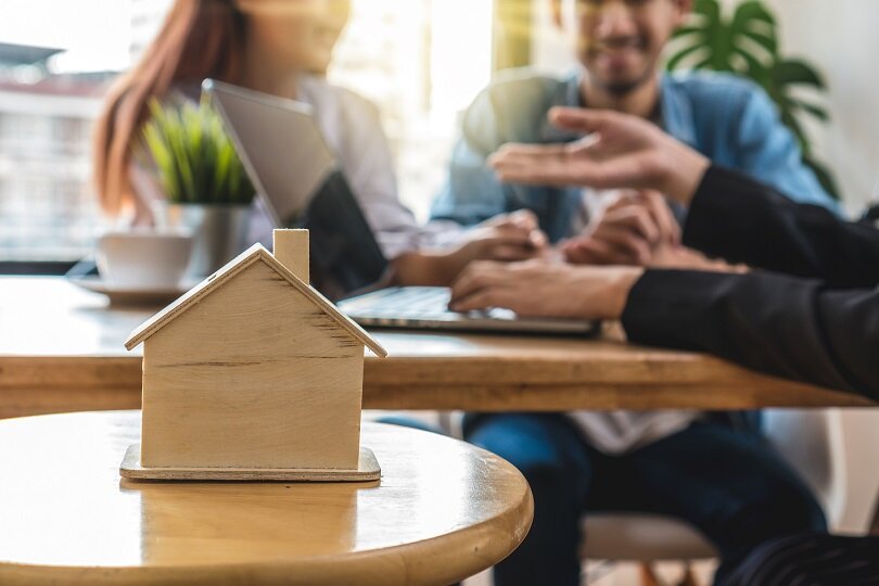 Closeup house model over the Sale representative offer the house price list and condition for purchase or rental on the working space table in new place,Moving and House Hunting concept