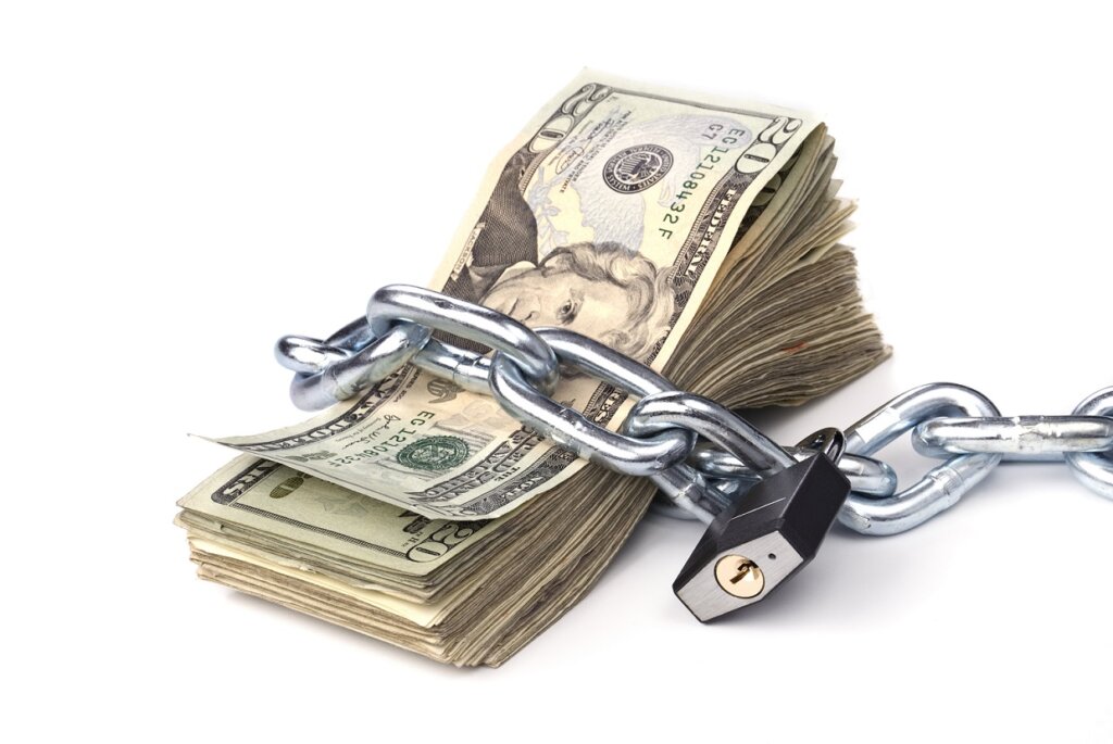 A stack of currency chained together and padlocked. Used for any money inference where money is tight or protected.