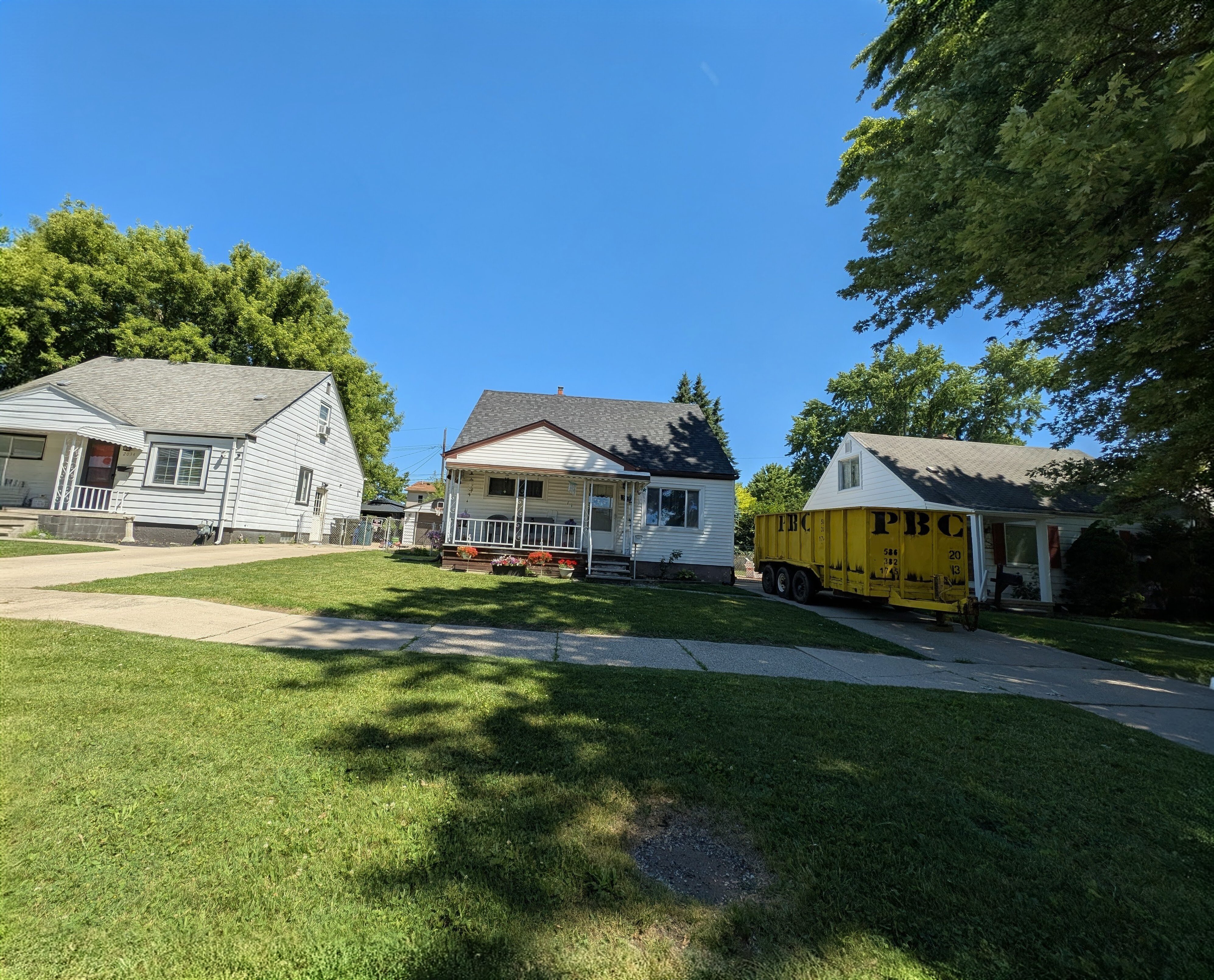 A Lincoln Park, MI bungalow Money Team Properties bought, mid-rehab with a cleanout dumpster in the driveway