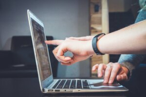 Real estate investors pointing at a laptop screen to advertise probate properties.