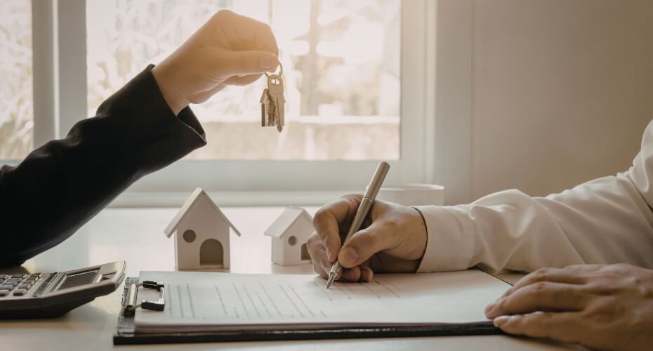 One party signing the closing documents, while the other hands over keys.