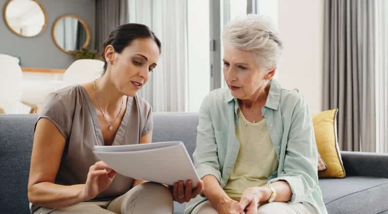 Adult daughter reviewing paperwork with her mother in an assisted living apartment