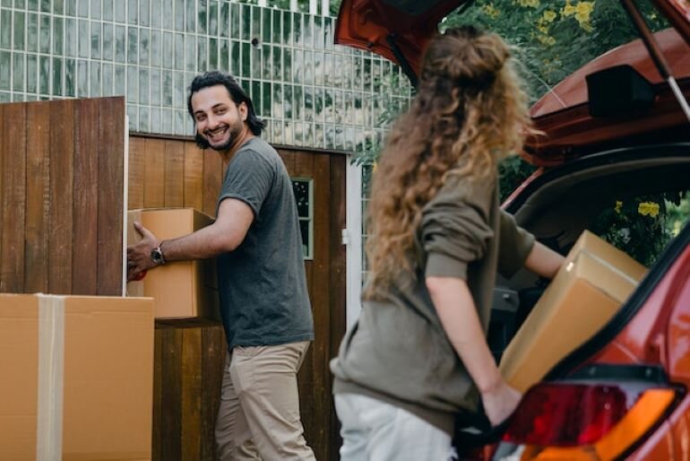 Two people are carrying some boxes.