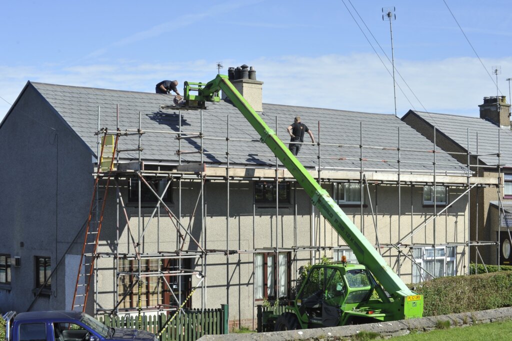 Men working to fix the roof of a house.