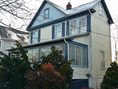 Abandoned vacant house in New Jersey with boarded-up windows, overgrown grass