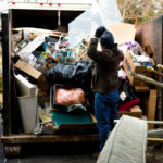 Worker loading debris from a hoarder house into a dumpster in Jersey City NJ