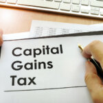 Hands holding documents with title capital gains tax text