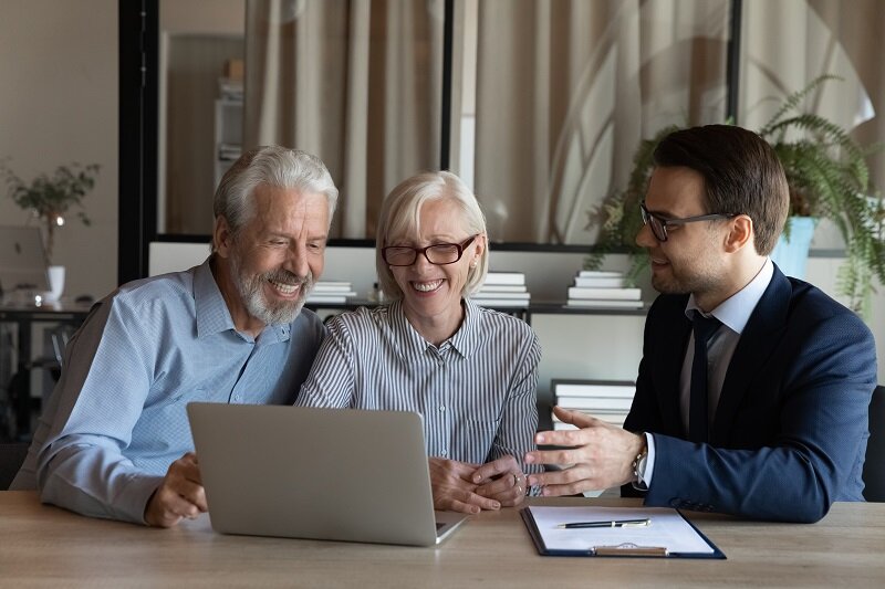 An elderly couple talking to a real estate agent about downsizing.