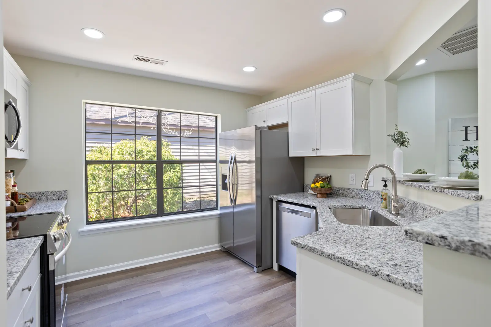 Renovated white kitchen with granite counters and stainless appliances