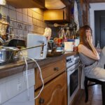cover photo for sell a house with tenants in new orleans-woman sitting in extermely cluttered kitchen smoking