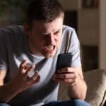 angry man looking at phone after call from direct home buyers