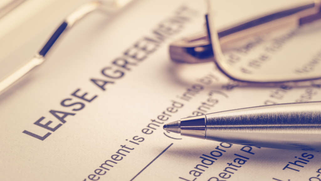 A close-up of a lease agreement document with a silver pen and eyeglasses resting on top. The words LEASE AGREEMENT are clearly visible, perfect for illustrating expert tips on selling your tenant occupied house.