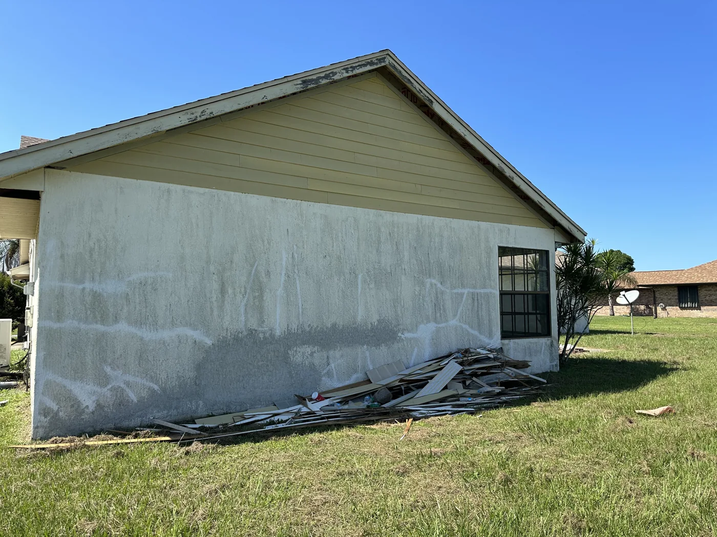 Side exterior wall with uneven surface patches and stacked materials