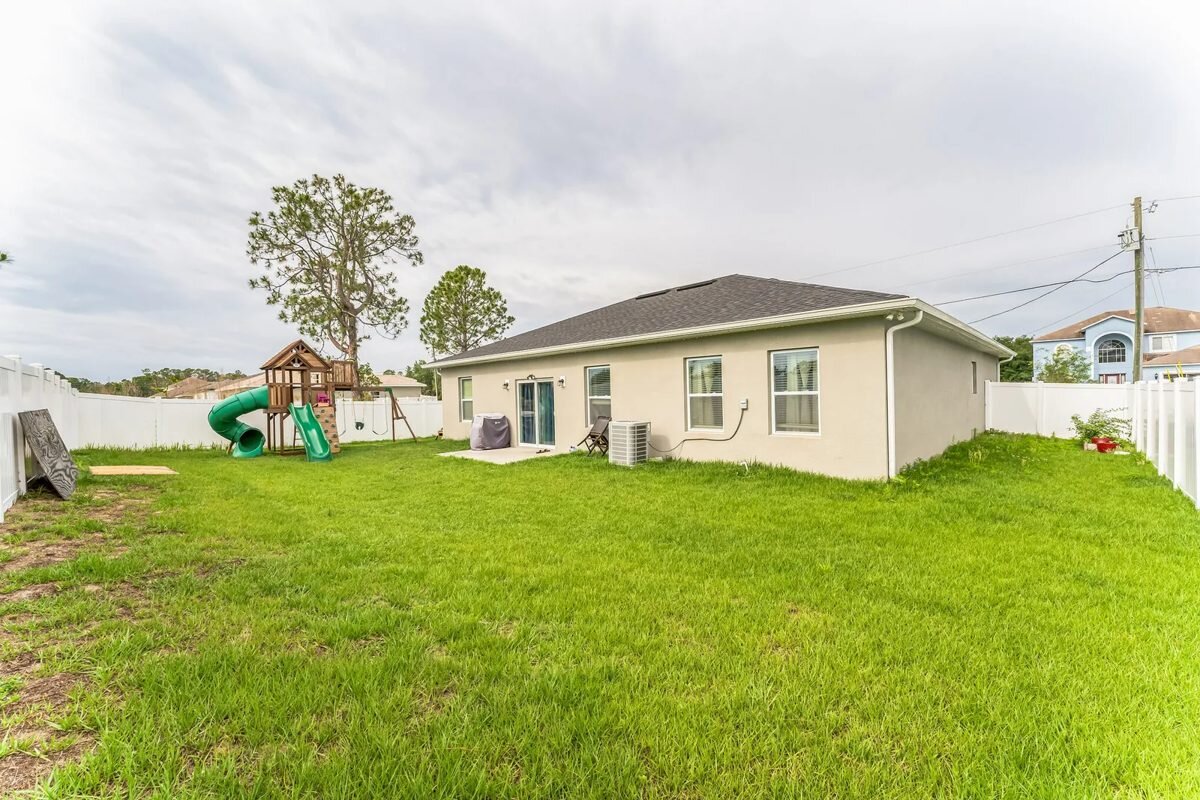 Rear exterior and fenced backyard of 1030 James Dr in Poinciana, Florida
