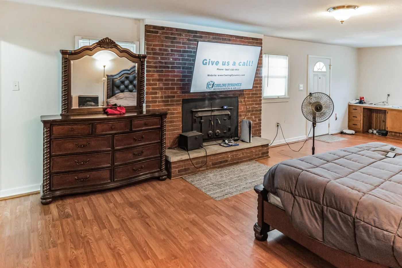 Furnished room with a brick fireplace, wood floor and ceiling fan