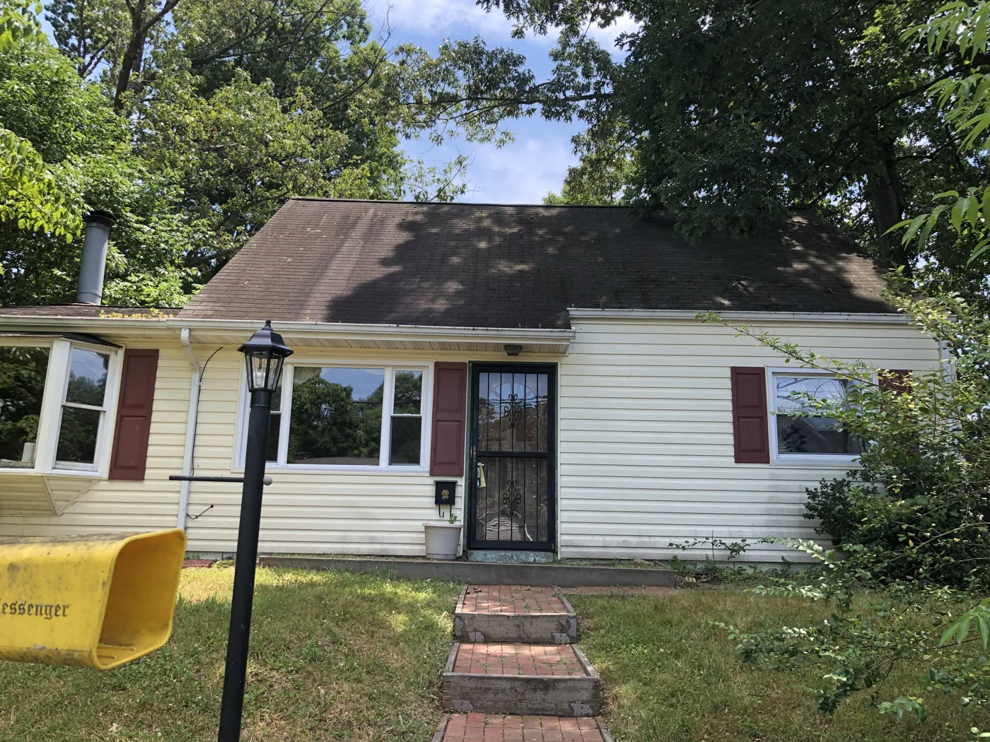 House with light siding, red shutters and a brick front walk
