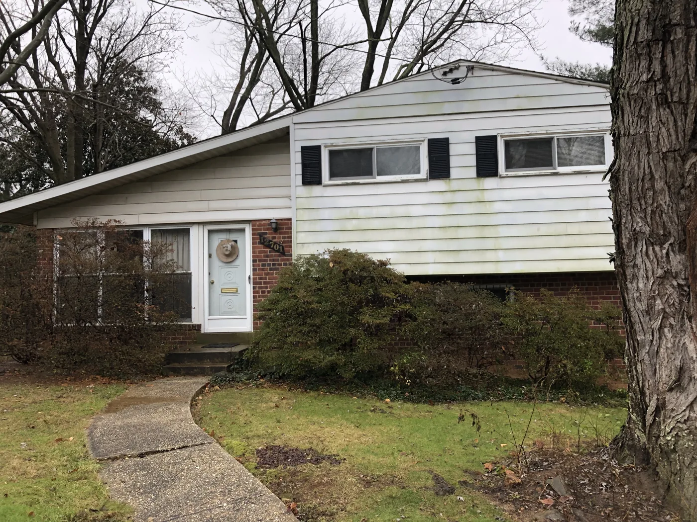 Split-level house with light siding and a curved front walkway