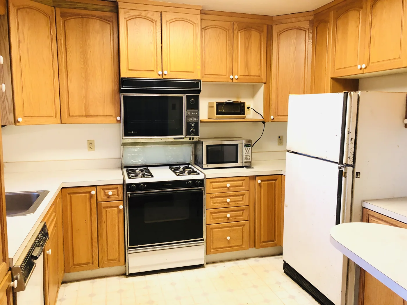 Dated kitchen with wood cabinets and white appliances