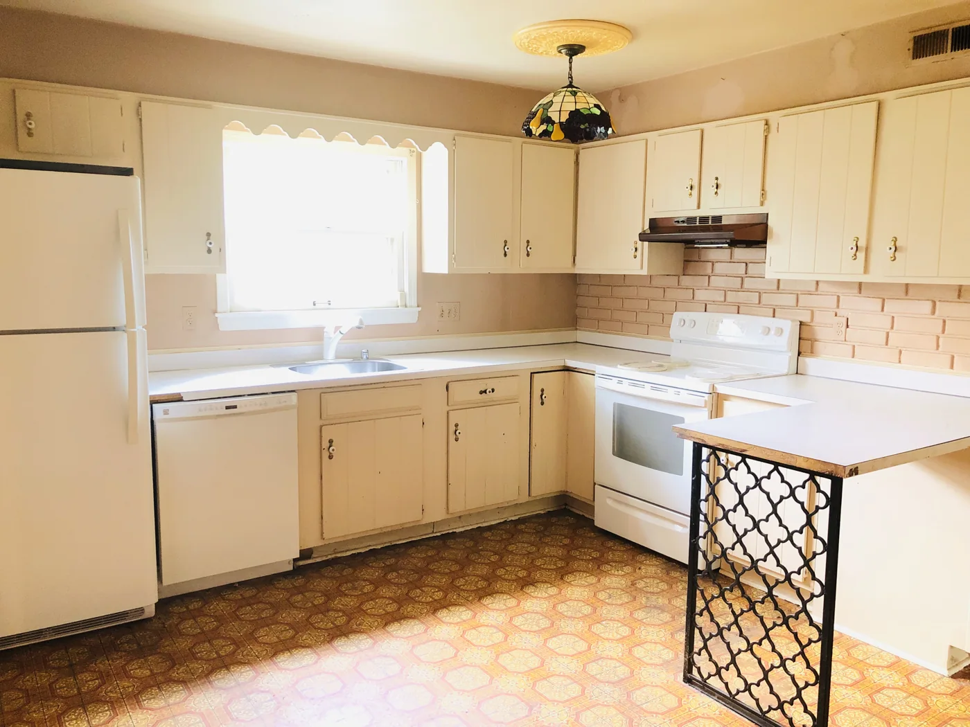 Kitchen with light cabinets, older appliances and patterned flooring