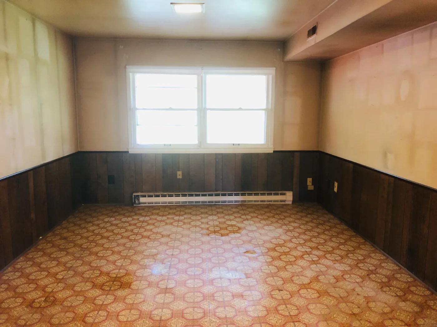 Empty room with patterned flooring and dark lower wall paneling