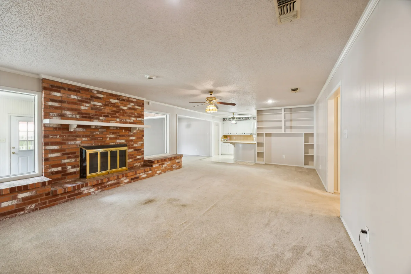 Living room with brick fireplace, carpet and a ceiling fan
