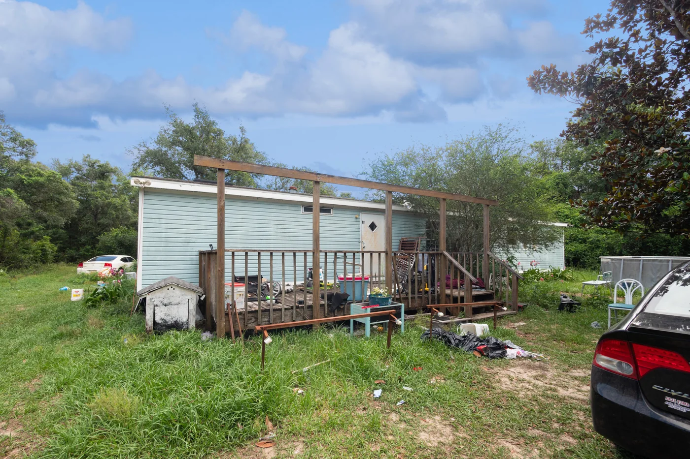 Mobile home with an open porch frame and items around the yard
