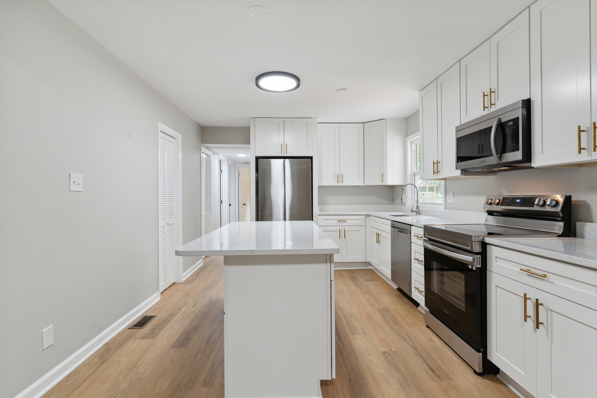 Kitchen at 22519 Joan Dr after renovation, with white cabinets, an island and stainless-steel appliances