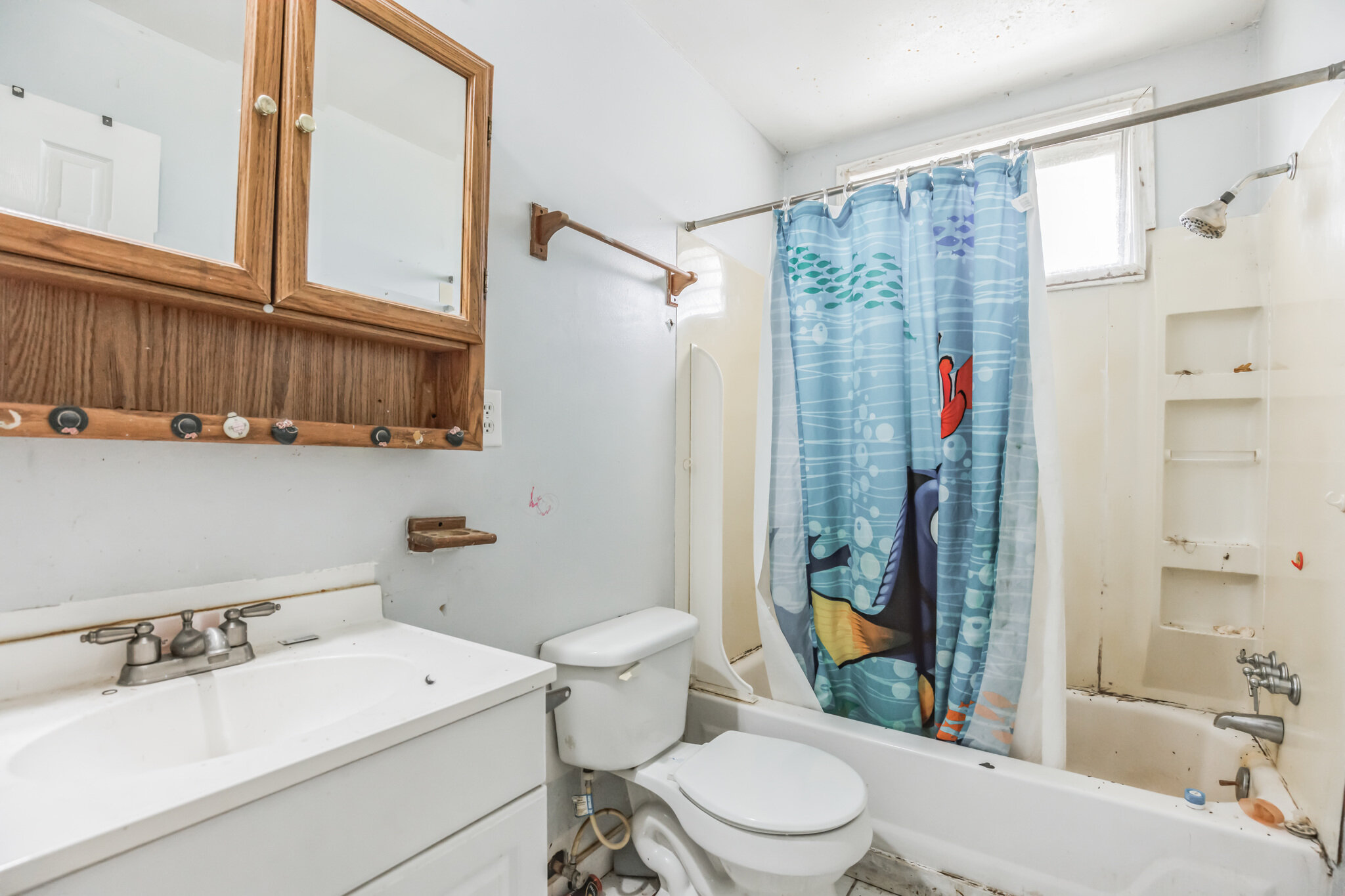 Bathroom at 22519 Joan Dr before renovation, with an older vanity and tub surround