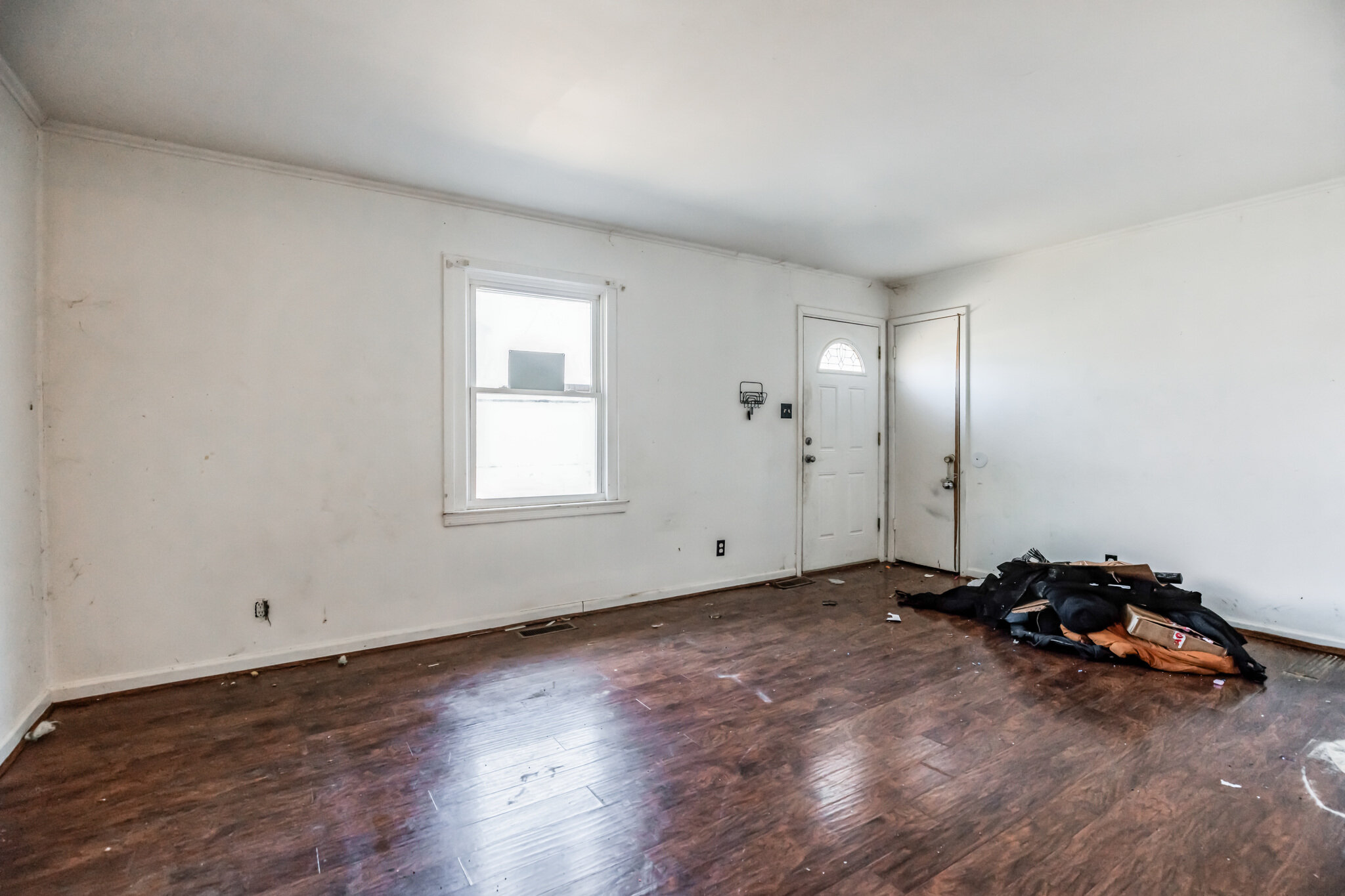 Living room at 22519 Joan Dr before updates, with worn wood flooring and items near the doorway