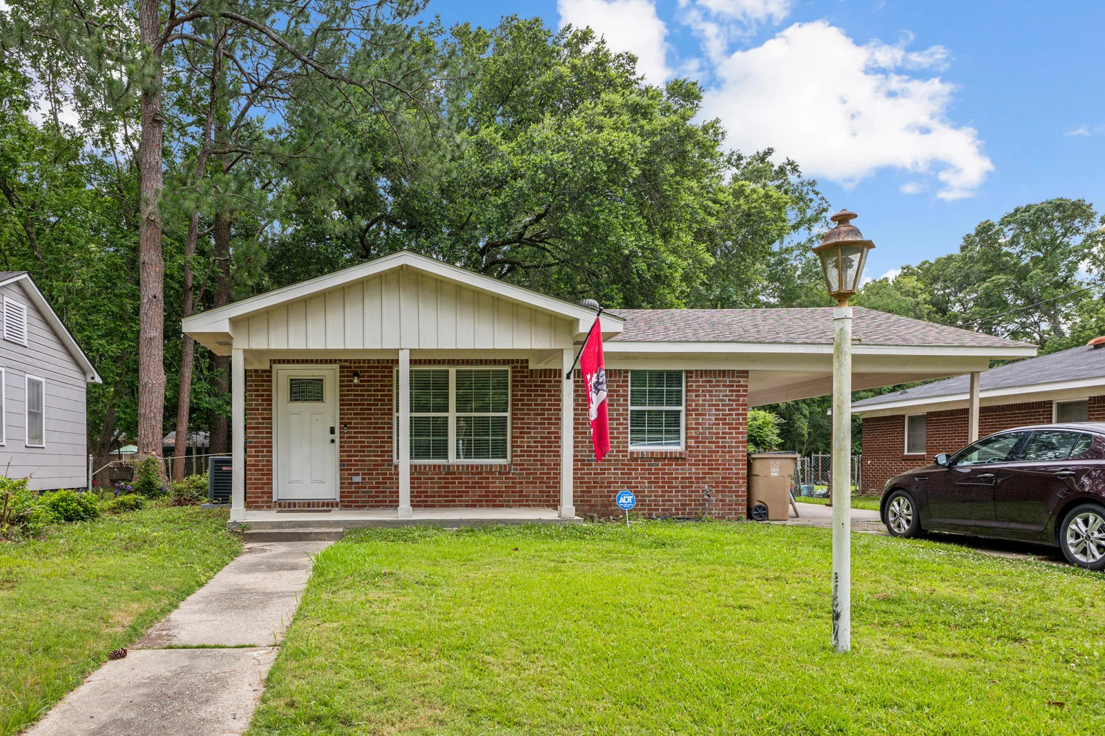 Front of 2405 Howell Avenue with brick facade, lawn and covered carport