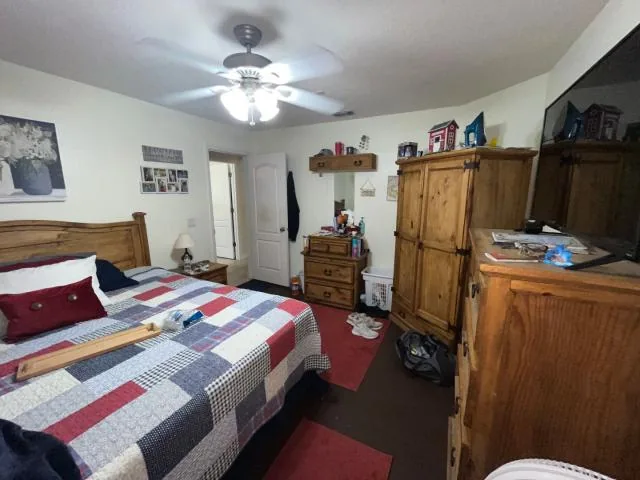 Furnished bedroom with wood wardrobes and a ceiling fan