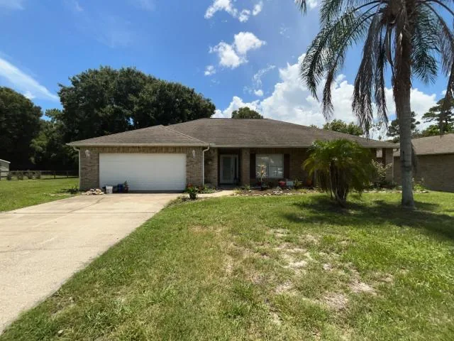 Single-story house with a garage, driveway and palm trees