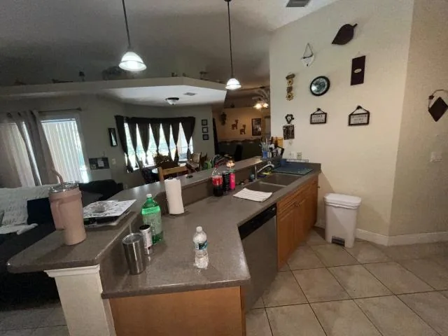 Kitchen with wood cabinets, tiled floor and belongings on the counters
