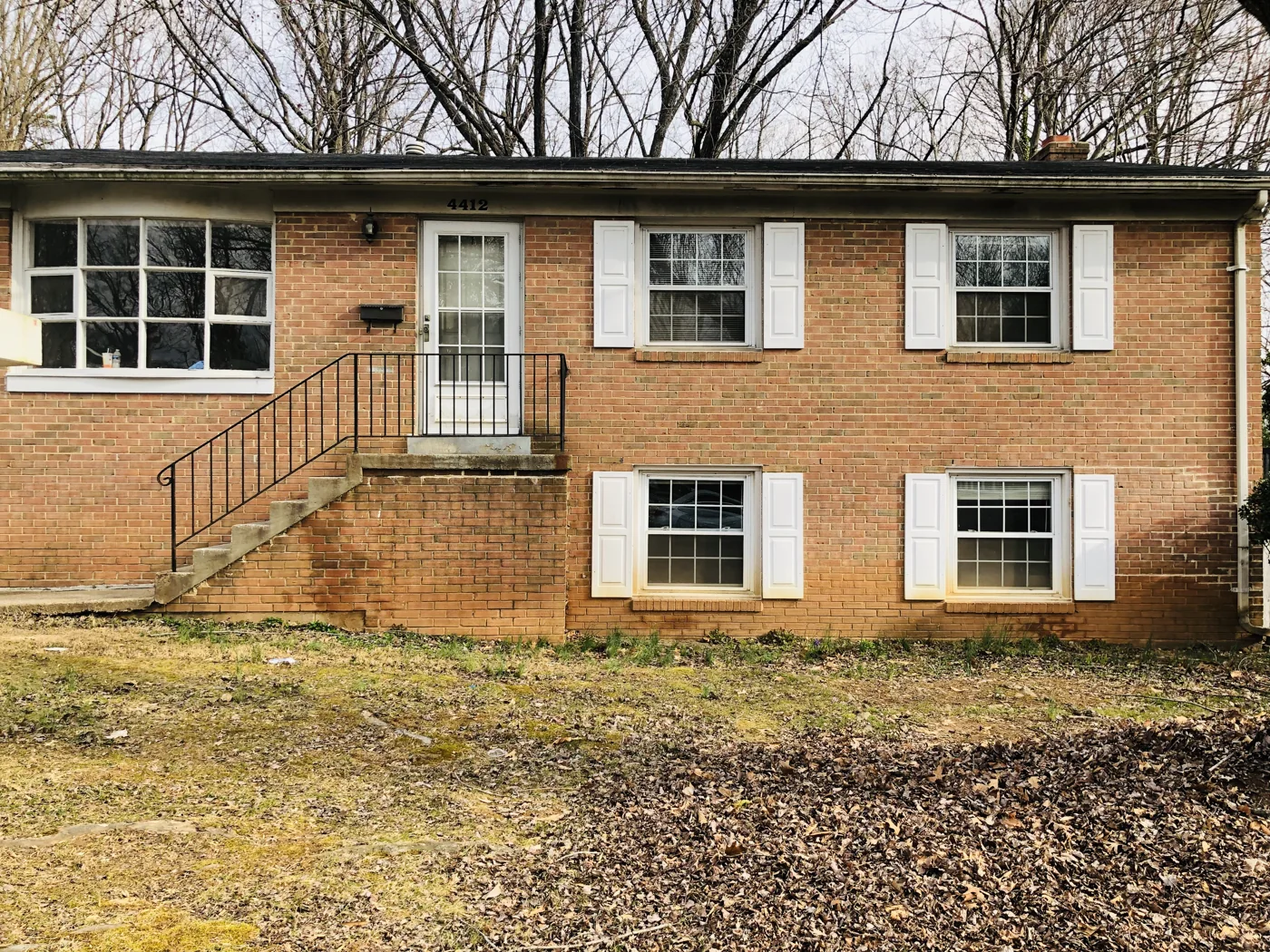 Brick split-level house with front steps and dark shutters