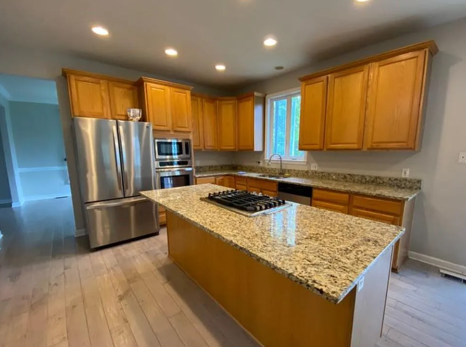 Kitchen at 5823 Montgomery Rd with wood cabinets, a stone-topped island and stainless-steel appliances