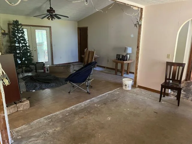 Interior before renovation with bare flooring and visible ceiling damage