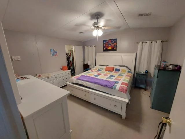 Bedroom with a colorful quilt and ceiling fan