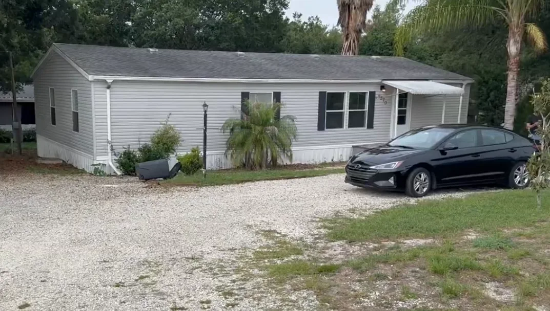 Mobile home with a gravel driveway and trees