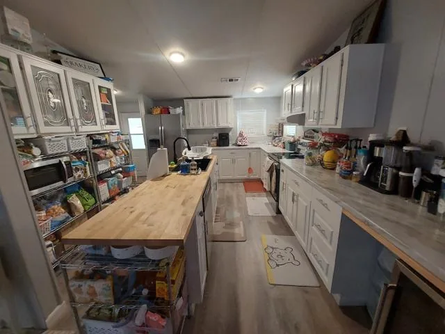 Kitchen with white cabinets, an island and wood-look flooring