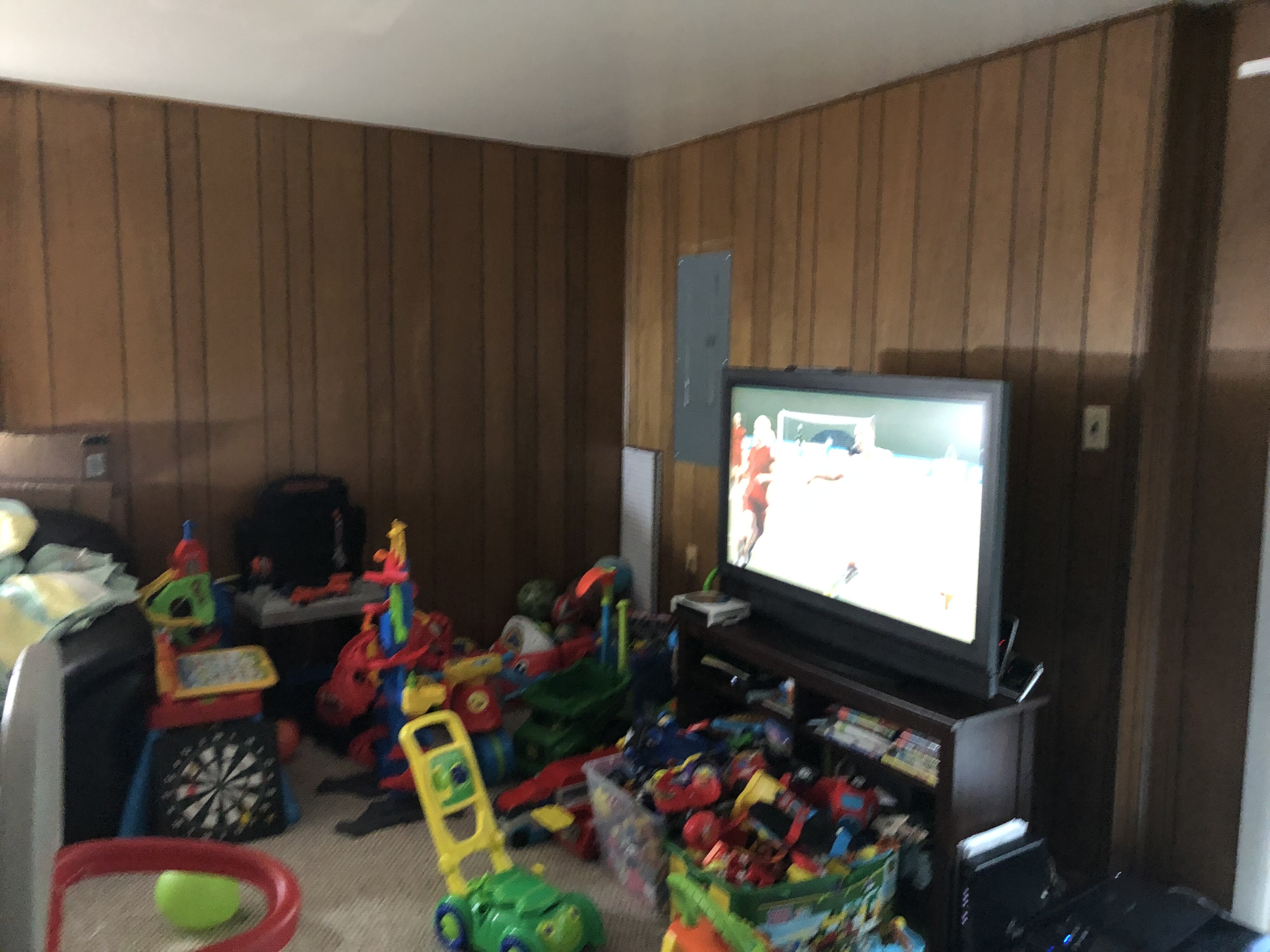 Living room at 14648 Bakersfield St with wood paneling, television and household belongings