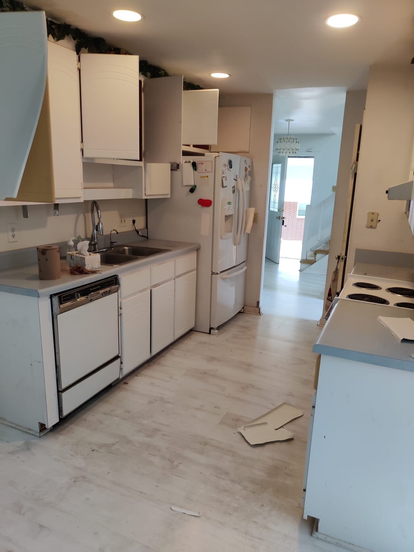 Kitchen at 77 Linda Dr with white cabinets, appliances and flooring needing attention