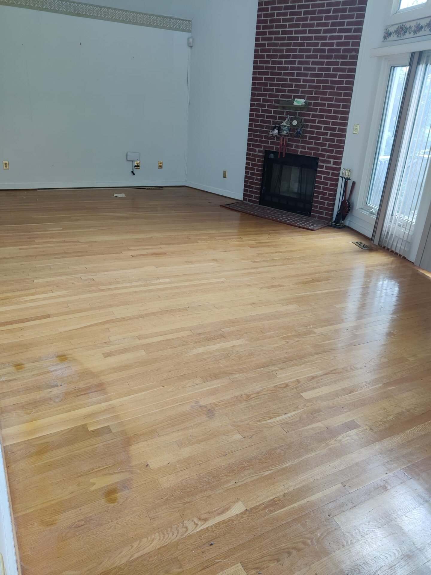 Living room at 77 Linda Dr with wood flooring, a brick fireplace and tall windows