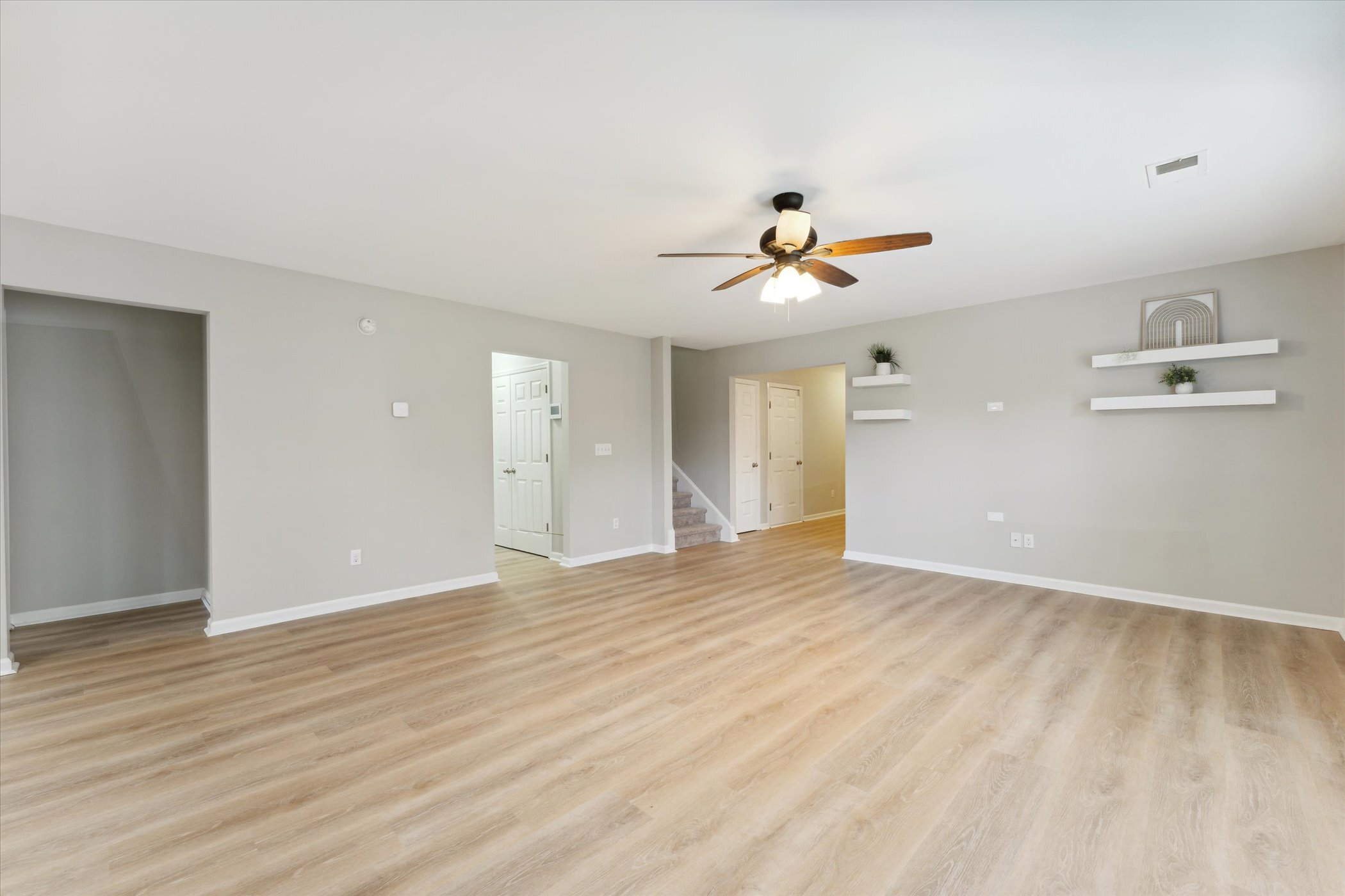 Empty living room at 445 Lions Den Dr after updates, with wood-look flooring and a ceiling fan