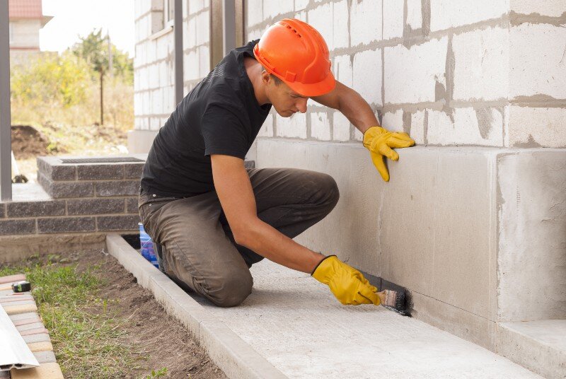 A construction worker finishing up some foundation work. 