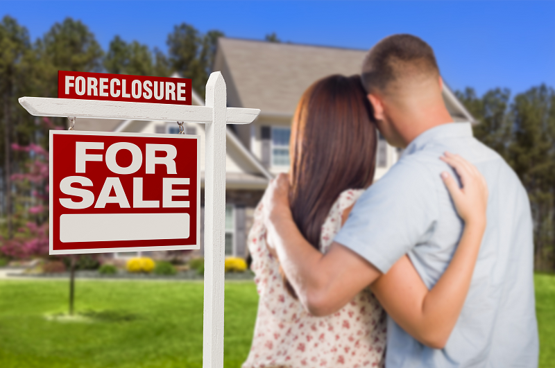 A couple hugging while looking at a "For sale" sign on their house in Green Bay, Wisconsin