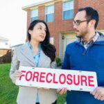 couple holding foreclosure sign