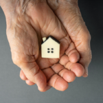 house model placed on palm by an elderly person