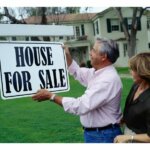 Couples putting up house for sale signage