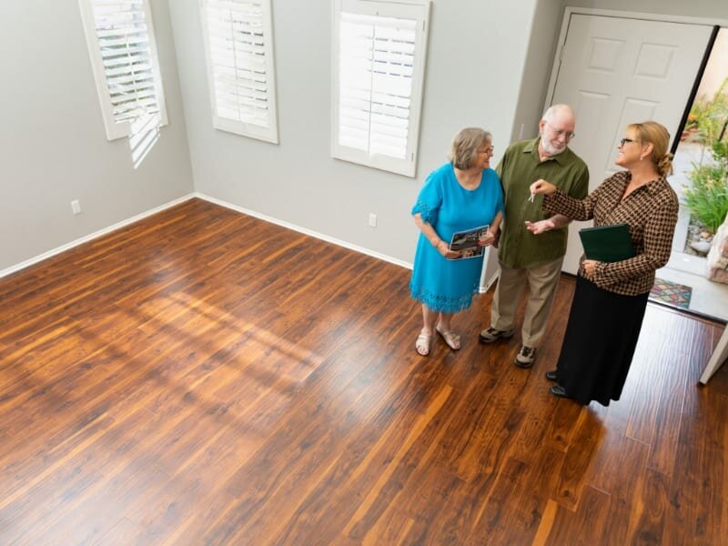 Female real estate agent handing new house keys to senior adult
